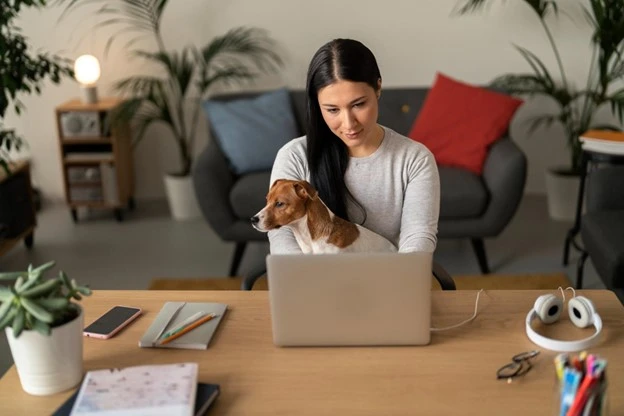 Image of dog on laptop while a lady is trying to use the laptop to launch a new business.
